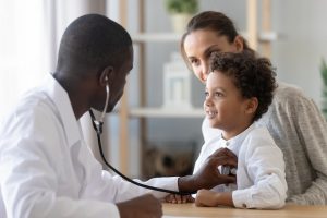 Family medicine physician using stethoscope on child patient during office visit documented with VoiceboxMD dictation software